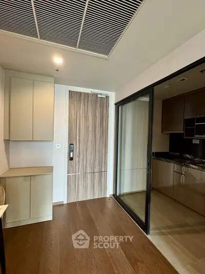Modern kitchen with sleek cabinets and glass sliding door in contemporary apartment.
