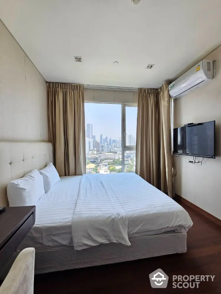 Modern bedroom with city view, featuring a comfortable bed and wall-mounted TV.