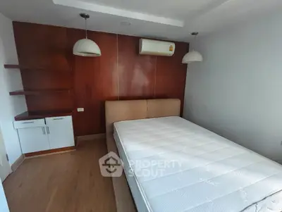 Spacious bedroom with modern design, featuring a comfortable bed and stylish wooden accents.