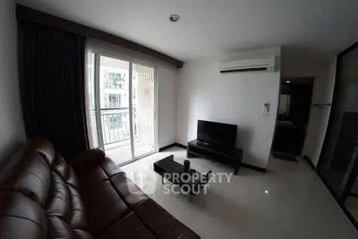 Modern living room with leather sofa, TV, and balcony access in a stylish apartment.