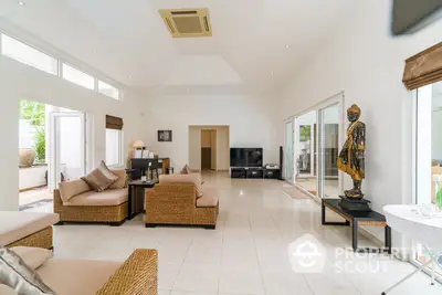 Spacious living room with high ceilings, natural light, and modern furnishings, leading to an inviting outdoor area.