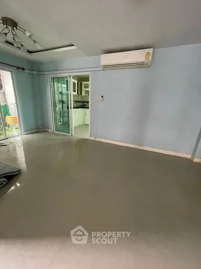 Spacious living room with air conditioning and sliding glass doors to kitchen.