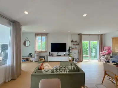 Spacious living room with modern decor and large windows offering natural light and garden view.
