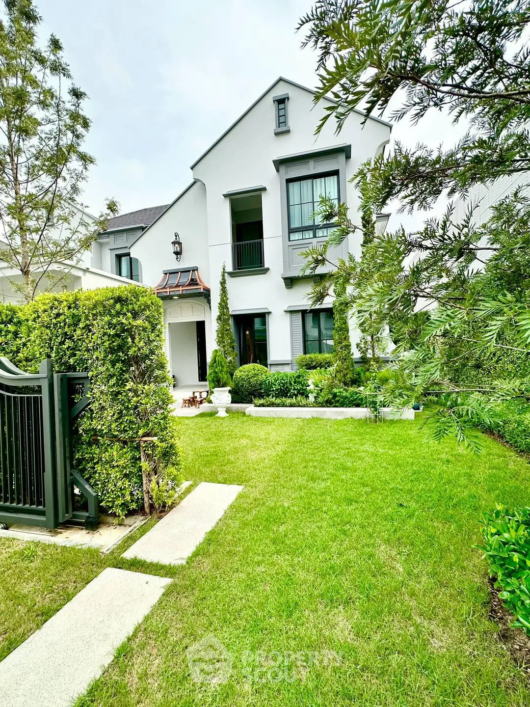 Charming two-story house with lush green garden and elegant facade, perfect for family living.