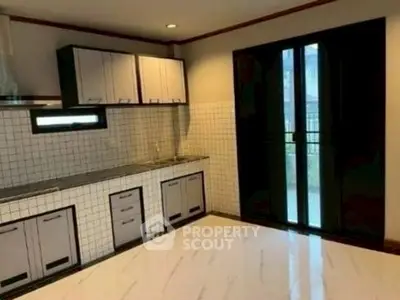 Spacious kitchen with modern cabinetry and tiled backsplash in a bright home.