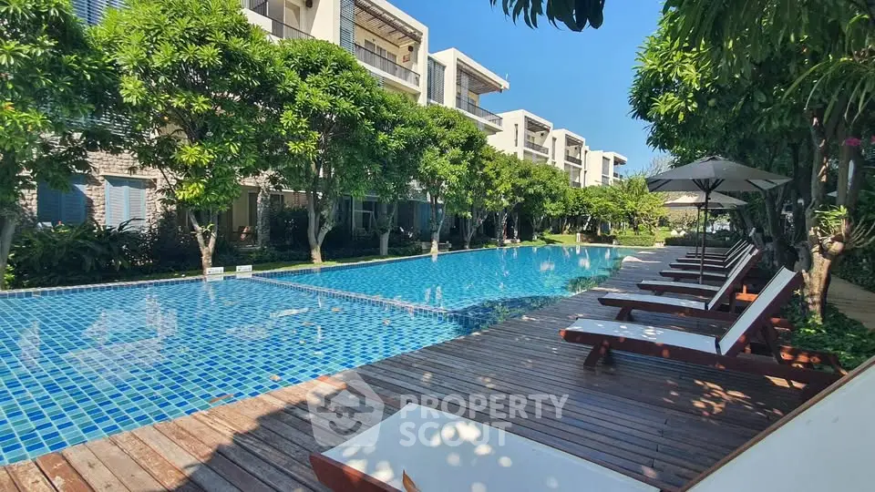 Luxurious poolside view with modern apartments and lush greenery