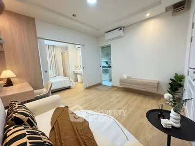Modern living room with cozy decor and open view into bedroom and kitchen.