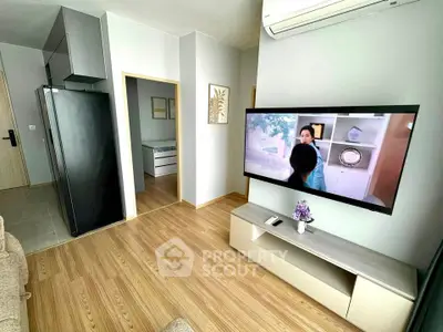 Modern living room with wall-mounted TV and sleek wooden flooring in a cozy apartment.