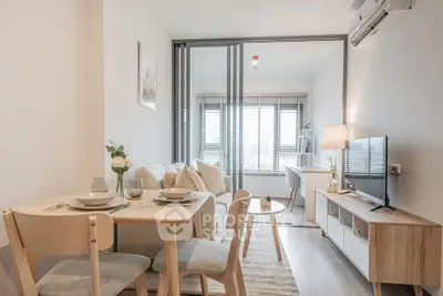 Modern living room with stylish furniture and natural light, featuring a cozy dining area and sleek TV setup.