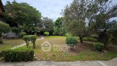 Spacious garden with lush greenery and paved pathway in serene residential area