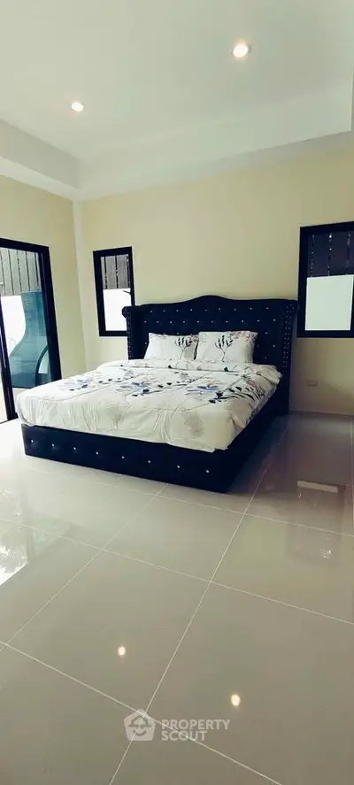 Spacious bedroom with elegant bed and large windows offering natural light.