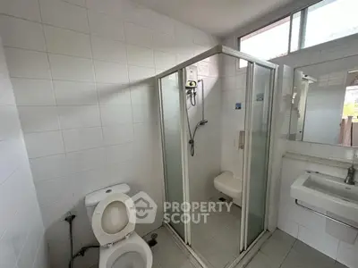Modern bathroom with shower cabin and white tiles in bright natural light