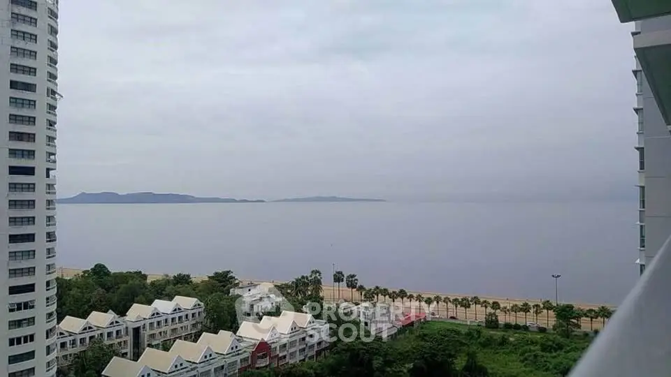 Stunning ocean view from high-rise balcony overlooking serene beach and lush greenery.