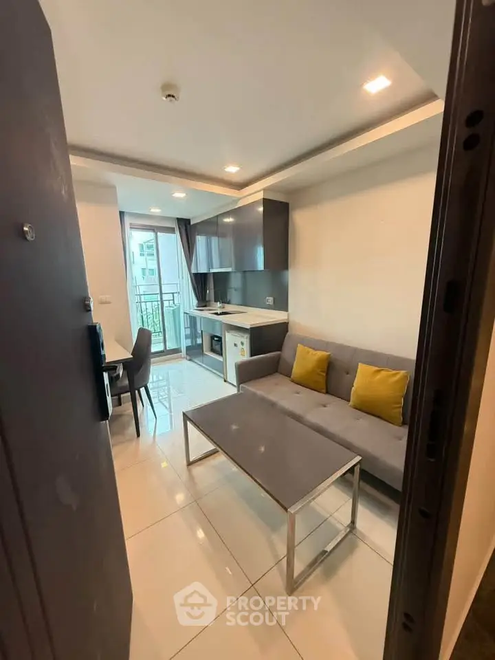 Modern living room with sleek kitchen and balcony access in a stylish apartment.