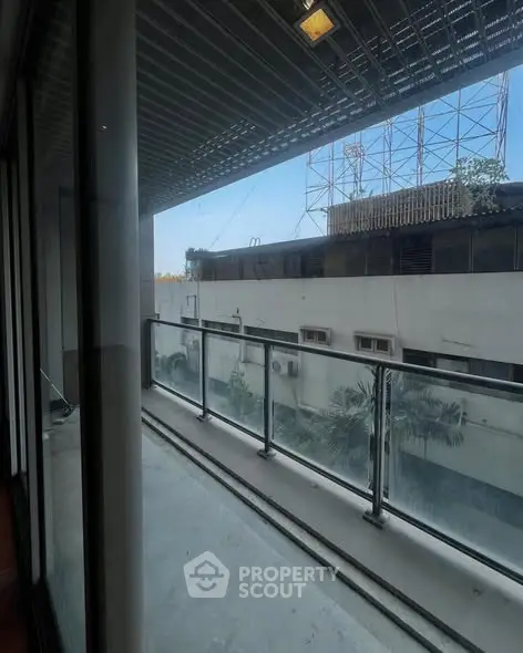 Spacious balcony with glass railing offering urban views and ample natural light.