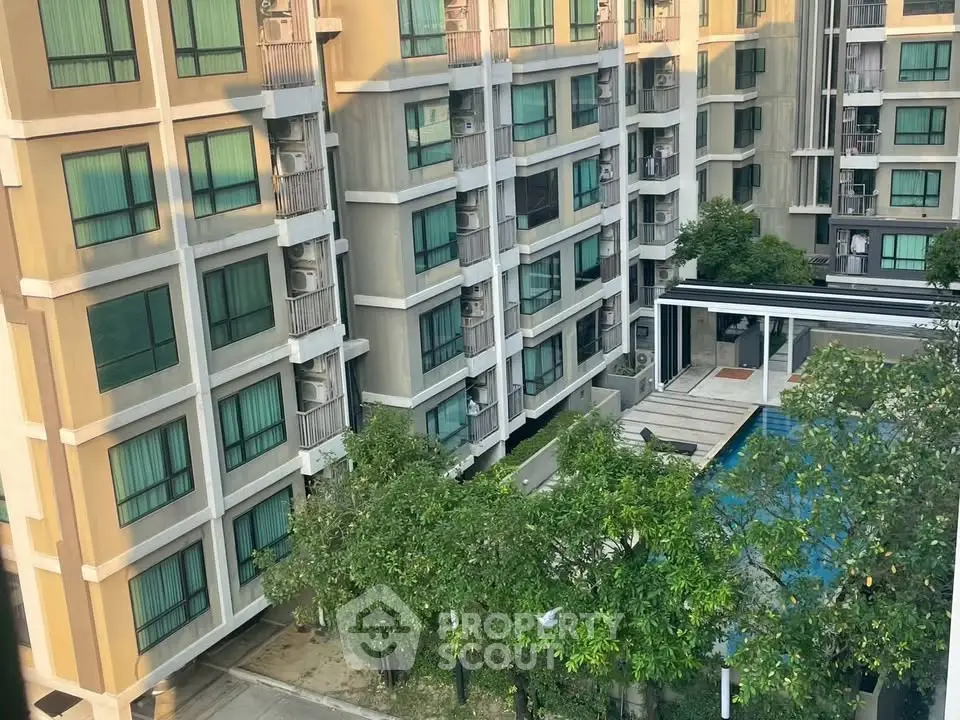 Modern apartment building with pool and lush greenery, offering a serene urban living experience.