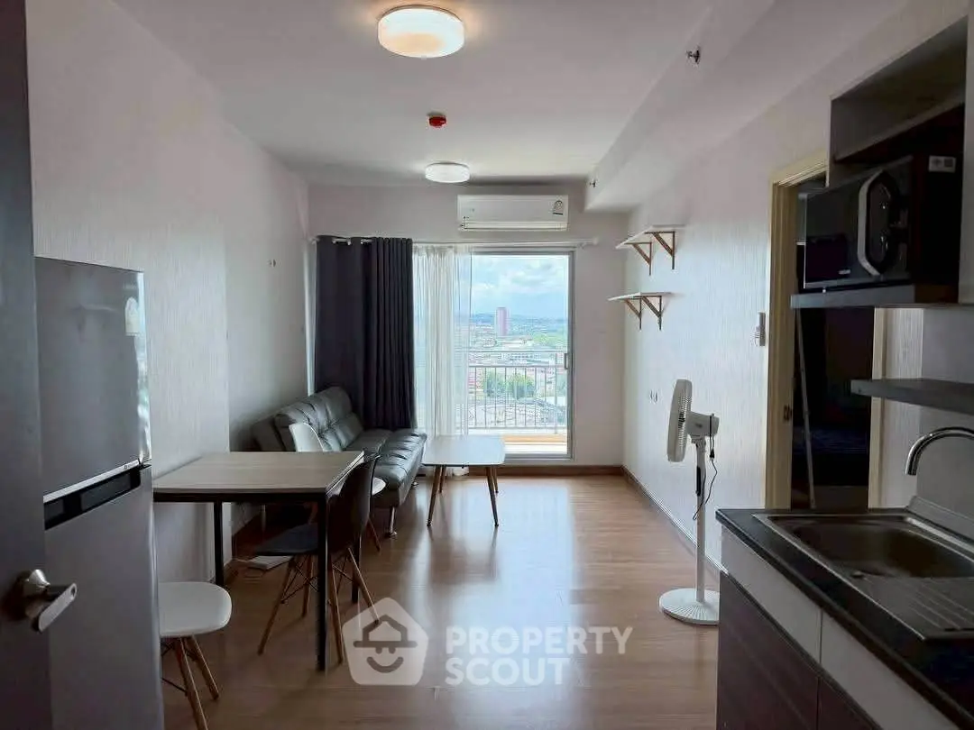 Modern living room with open kitchen and city view, featuring sleek furniture and natural light.