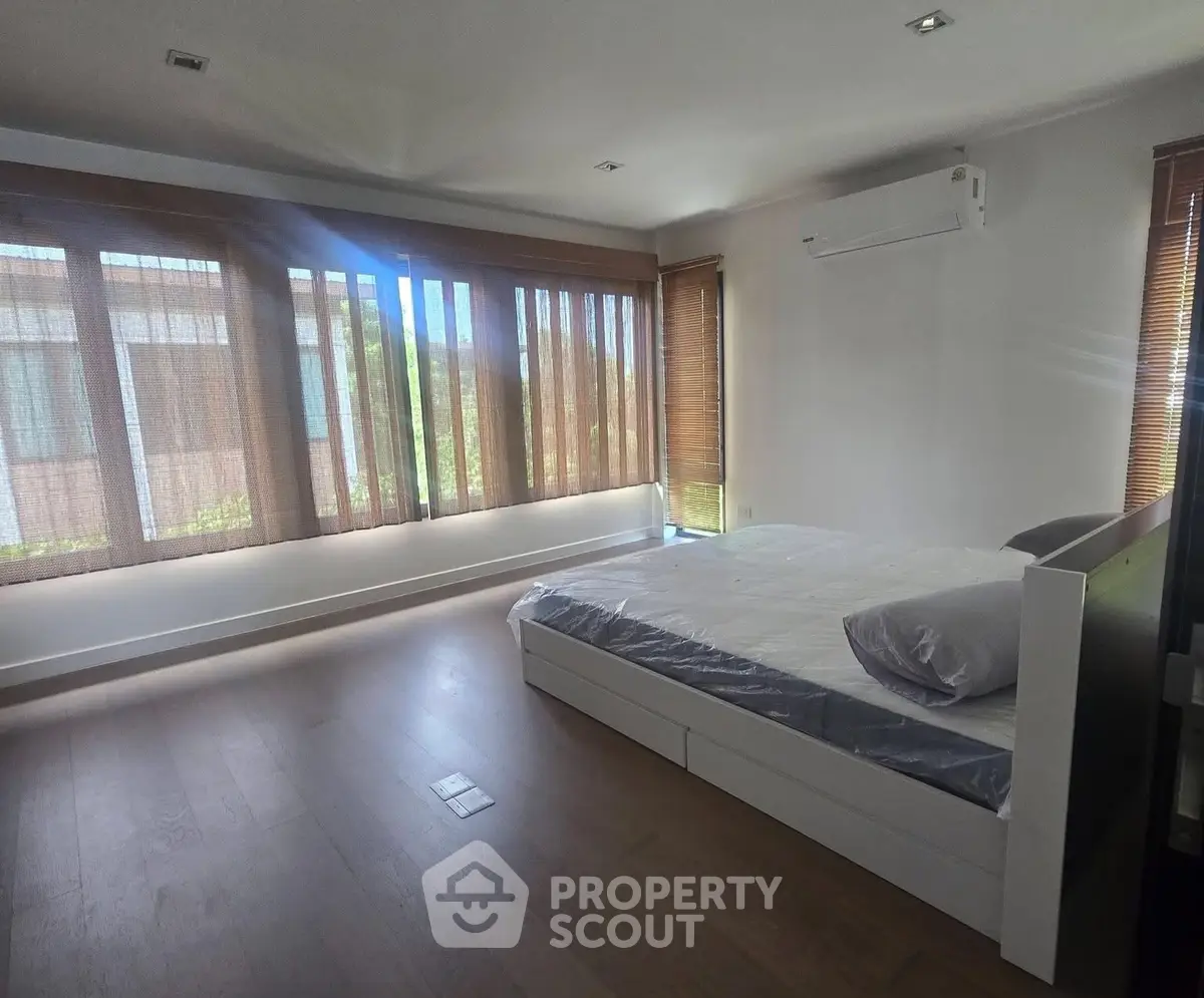Spacious bedroom with large windows and modern air conditioning unit, offering ample natural light and comfort.
