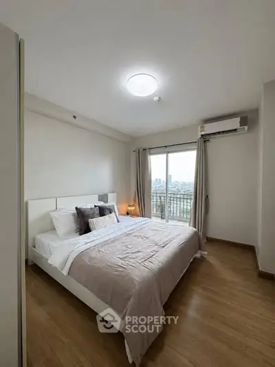 Spacious bedroom with modern decor and city view balcony access.