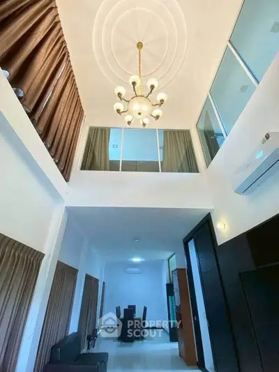 Spacious modern living room with high ceiling and elegant chandelier in a stylish apartment.