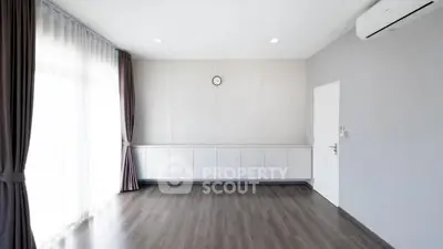 Spacious empty room with wooden flooring and air conditioning, ideal for customization.