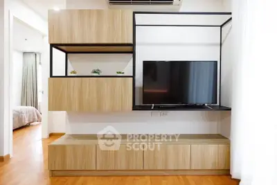 Modern living room with sleek wooden cabinetry and mounted TV, showcasing minimalist design and functionality.