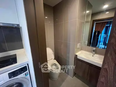 Modern bathroom with sleek design and integrated laundry area in a contemporary apartment.