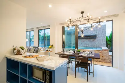 Modern open-plan dining and living area with stylish chandelier and pool view.