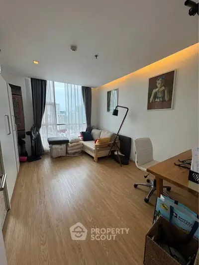 Modern living room with wooden flooring, large window, and stylish decor in a high-rise apartment.