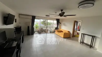 Spacious living room with modern decor and large windows opening to a balcony with a view.