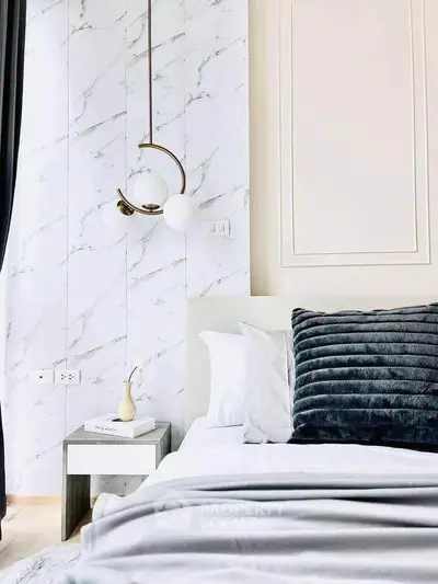 Luxurious bedroom with modern decor and elegant lighting, featuring a plush pillow and marble accent wall.