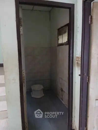 Compact bathroom with basic amenities and tiled walls, ideal for budget-conscious buyers seeking functionality.