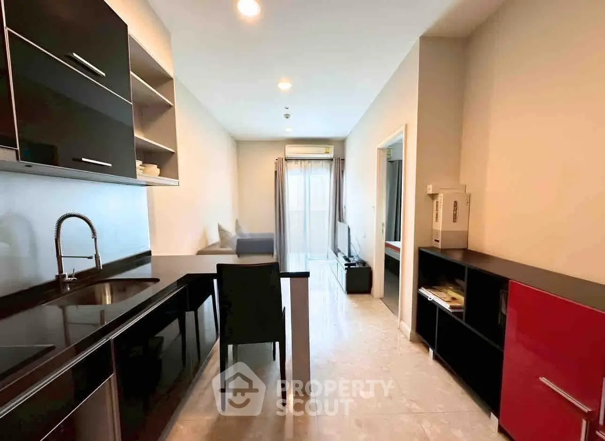 Modern open-layout kitchen and living area with sleek black cabinetry and bright natural light.