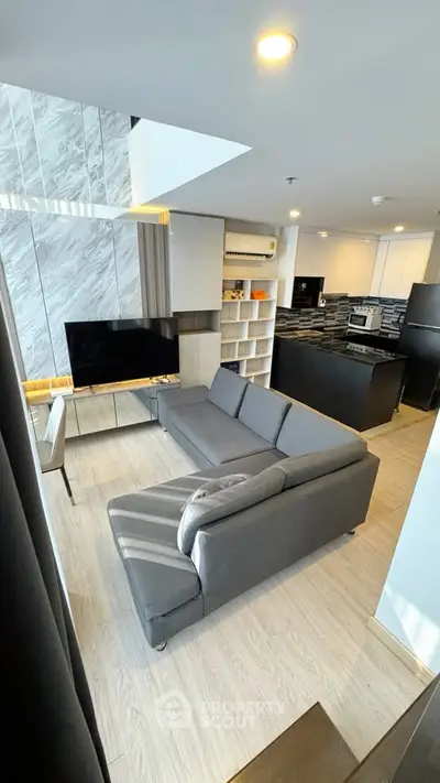Modern living room with sleek design and open kitchen layout in a stylish apartment.