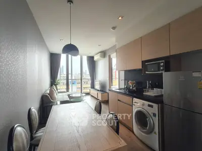 Modern kitchen with open layout, featuring washing machine and city view from large windows.