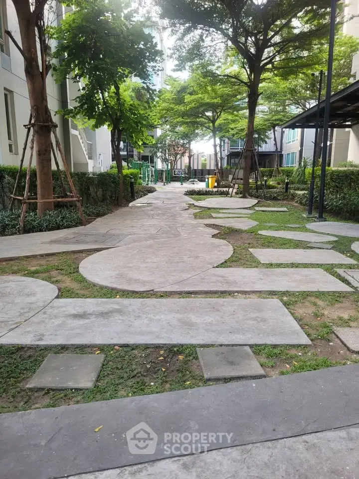 Charming garden pathway in modern residential complex with lush greenery and contemporary design.