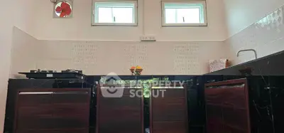 Modern kitchen with sleek dark cabinets and gas stove under natural light.