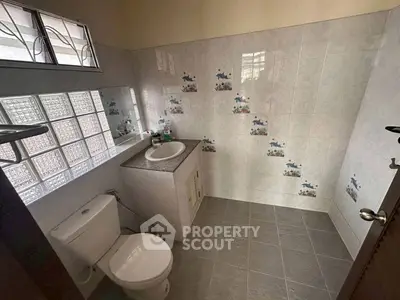 Charming bathroom with decorative tiles and natural light, perfect for a cozy home.