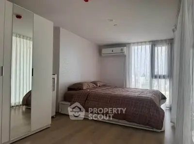 Spacious bedroom with modern decor and large windows offering natural light.