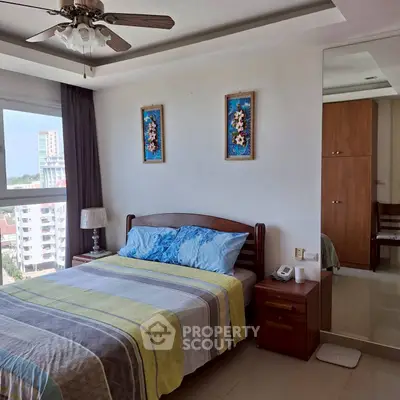 Spacious bedroom with modern decor and city view, featuring a cozy bed and stylish ceiling fan.