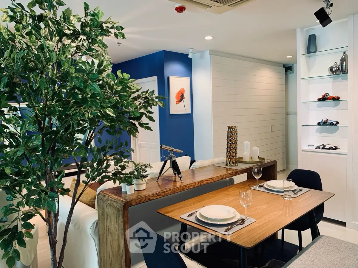 Stylish modern living room with dining area, featuring elegant decor and vibrant blue accent wall.