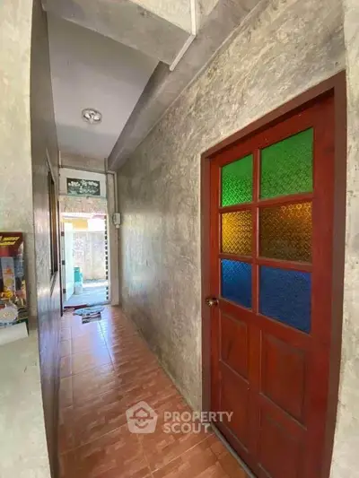 Charming hallway with colorful stained glass door and tiled flooring in a cozy home.