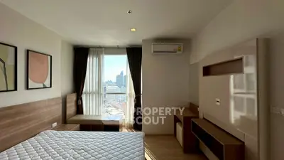 Cozy bedroom with city view and modern furnishings in a high-rise apartment.