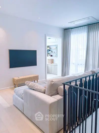 Modern living room with cozy sofa and wall-mounted TV, featuring elegant decor and natural light.
