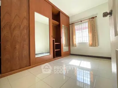 Spacious bedroom with large wooden wardrobe and natural light