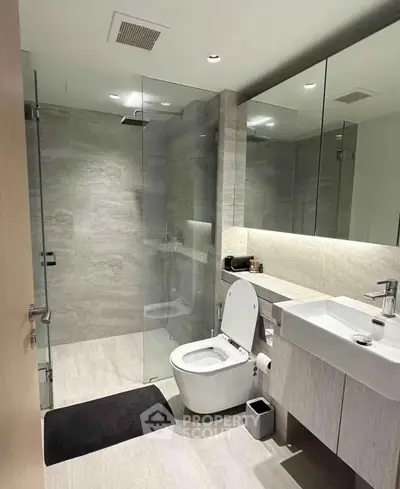 Modern bathroom with glass shower and sleek fixtures in luxury apartment.