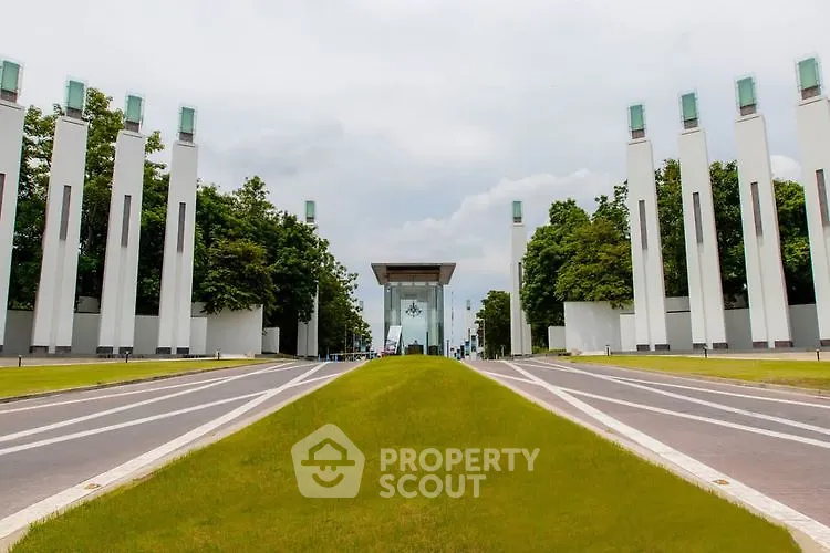 Modern architectural entrance with tall pillars and lush greenery