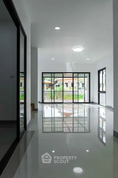 Spacious modern living room with large windows and glossy floors