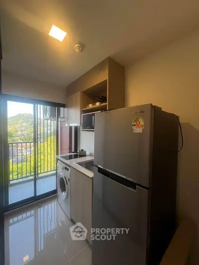 Modern kitchen with balcony view, featuring fridge and washing machine in compact layout.