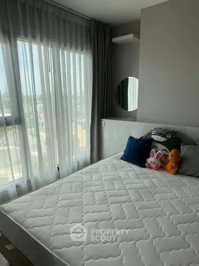 Cozy bedroom with large window and plush toys, offering natural light and a serene atmosphere.